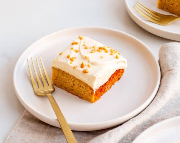 Squares of maple cake topped with whipped cream on dessert plates with forks.