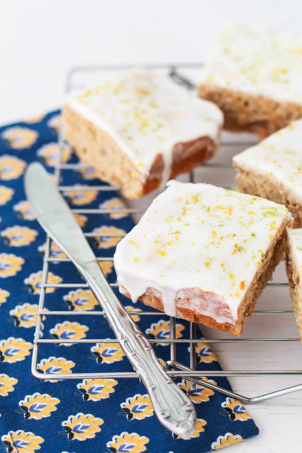 Squares of carrot cake bars on a cooling rack topped with glaze.