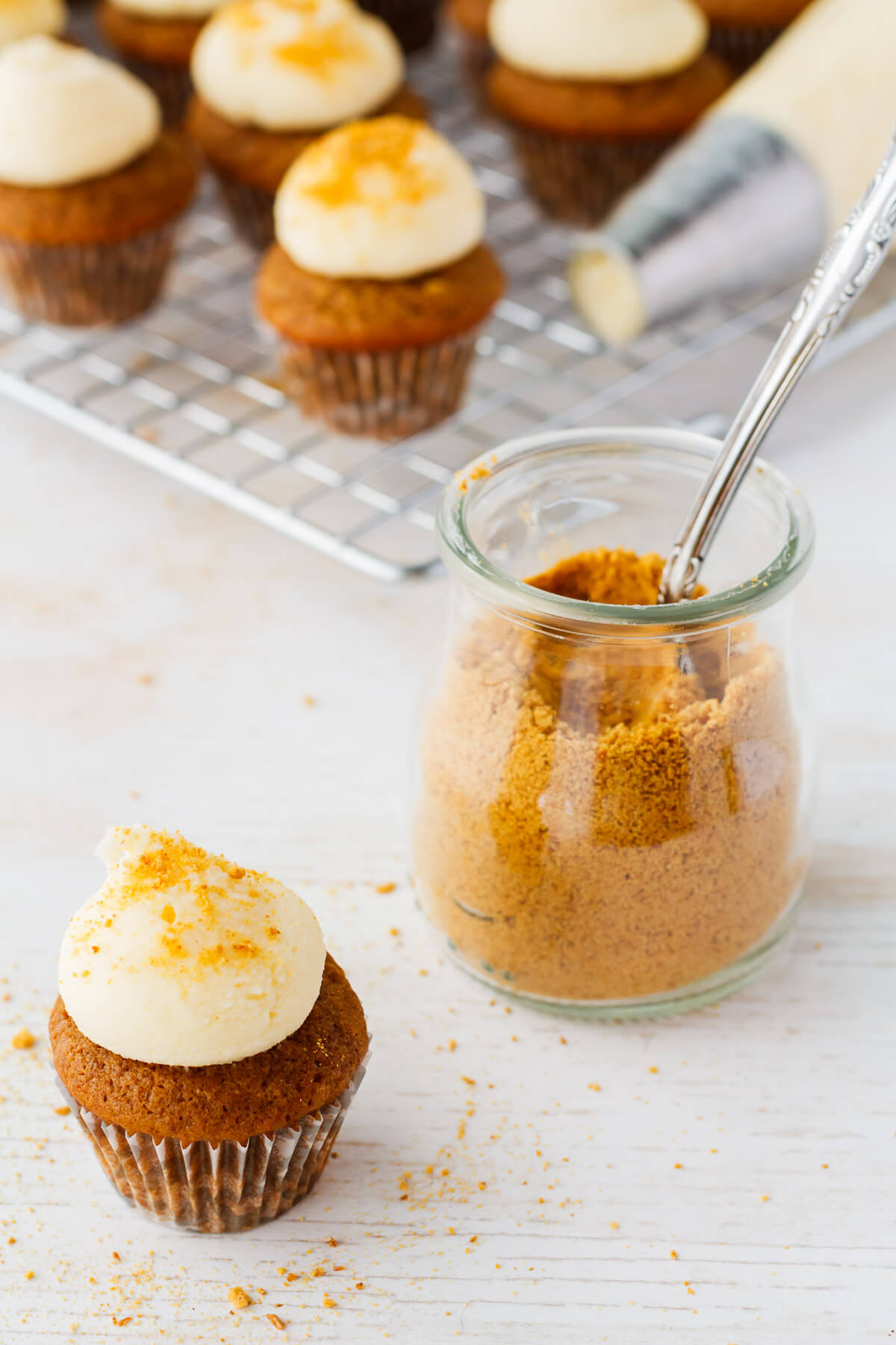 Topping spice cupcakes with thick cream cheese frosting and graham cracker crumbs.