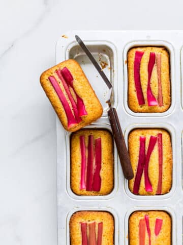 Removing orange rhubarb cakes from mini loaf cake pans with a mini offset spatula.