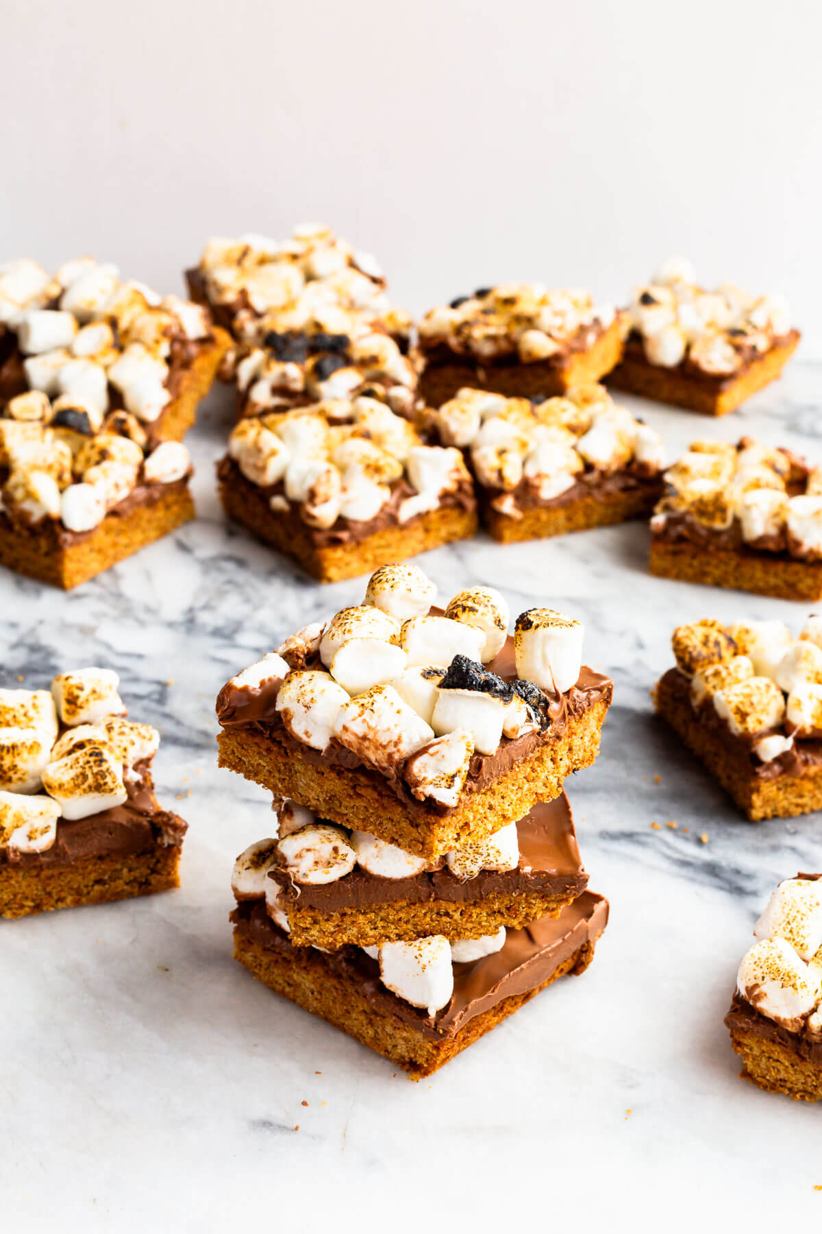 A stack of s'mores bars made with a graham cracker crust, milk chocolate filling, and toasted marshmallows on top.