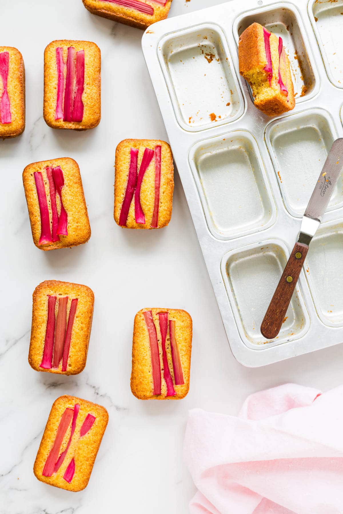 Unmoulding rhubarb orange cakes from pan with a mini offset spatula.
