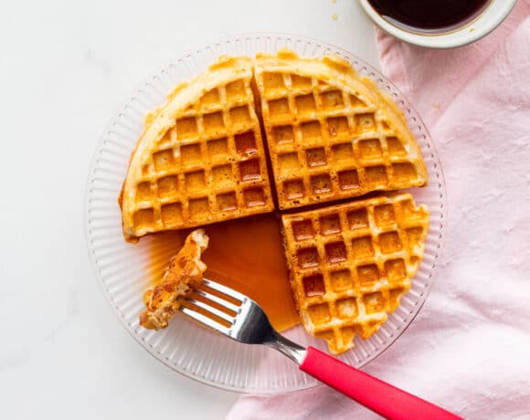 A plate with a sourdough discard waffle drizzled with lots of maple syrup.