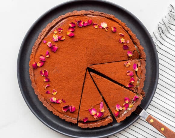 Cutting a chocolate ganache tart into slices to serve it.