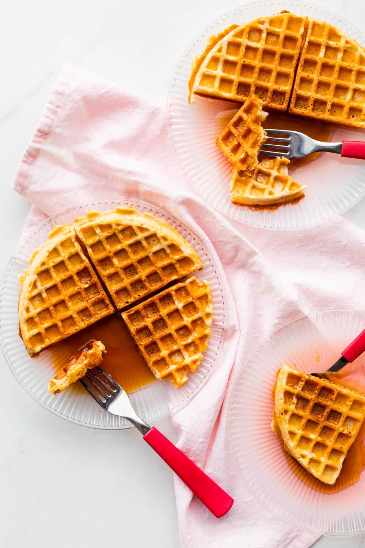 Enjoying plates of sourdough discard waffles served with lots of maple syrup.