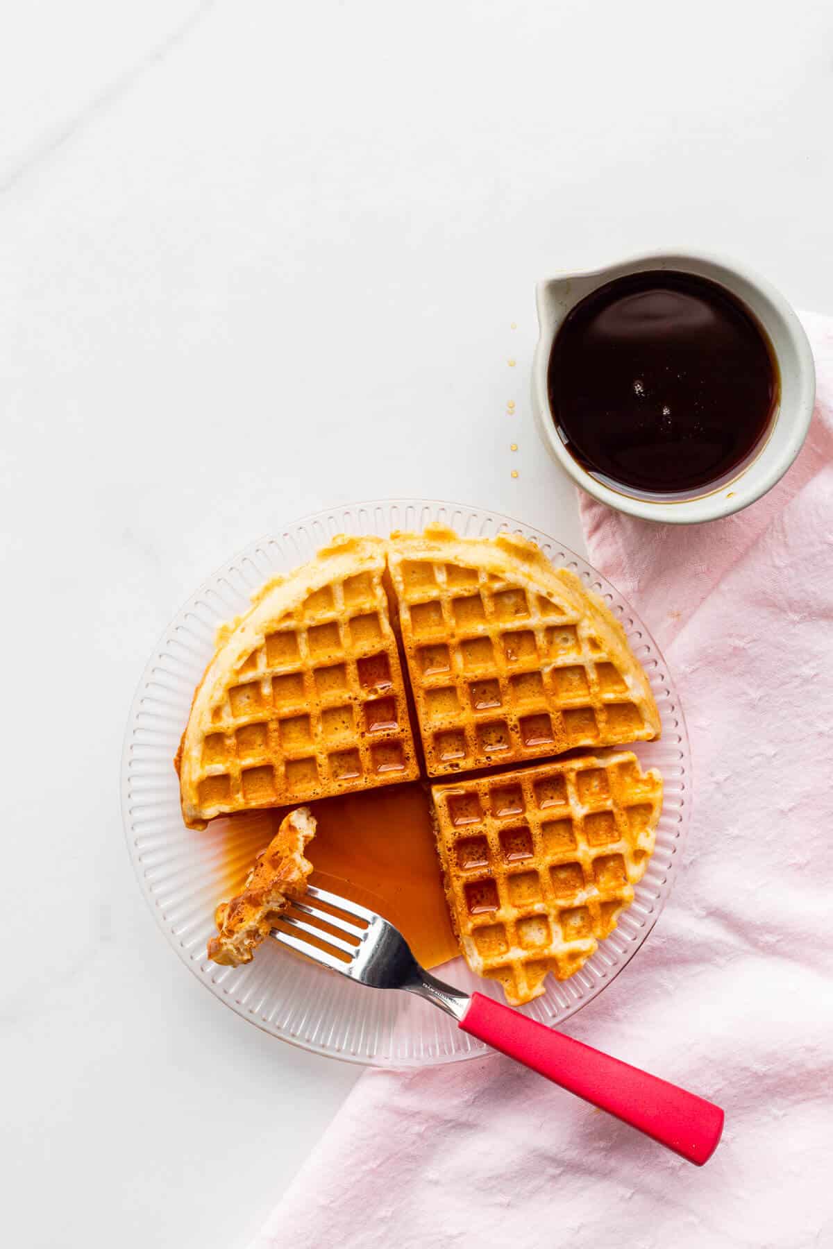 A plate of waffles served with a generous amount of maple syrup.