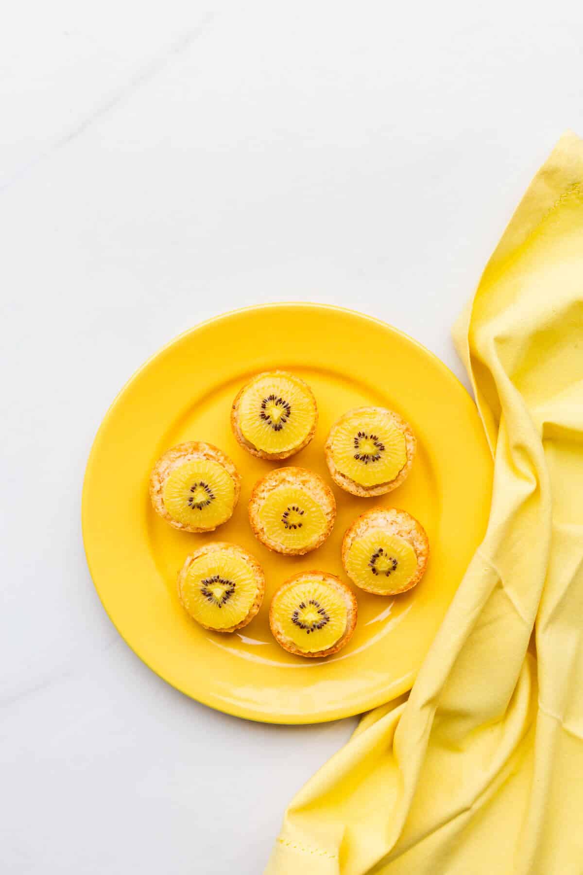 A plate of coconut and golden kiwi cakes ready to be eaten.