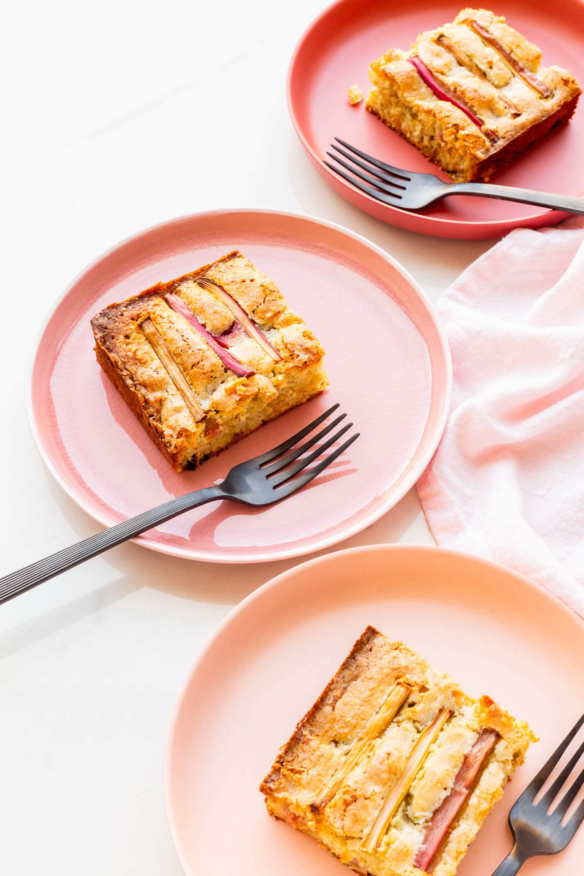 Squares of moist rhubarb cake on plates.