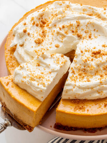 Serving a slice of pumpkin cheesecake topped with whipped cream.