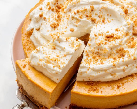 Serving a slice of pumpkin cheesecake topped with whipped cream.