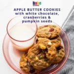A plate of white chocolate chip and dried cranberry cookies served with a glass of milk.