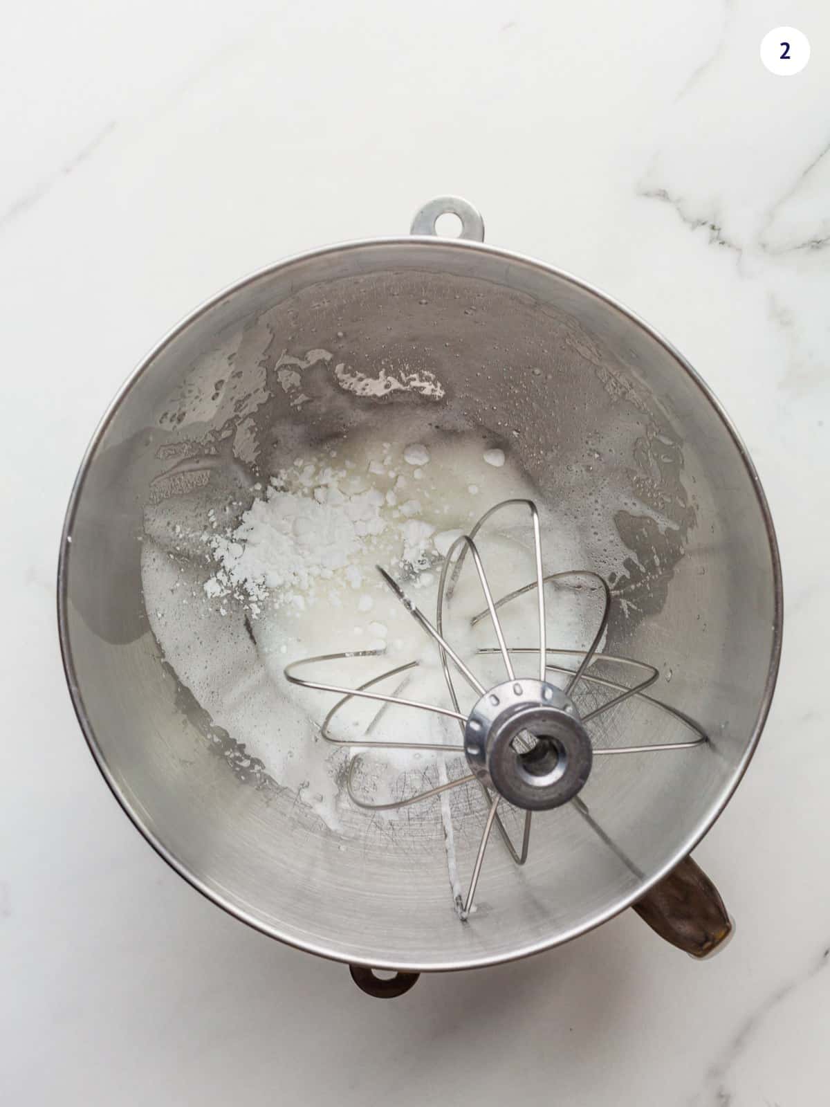 Slowly adding icing sugar to whipped egg whites to make royal icing.