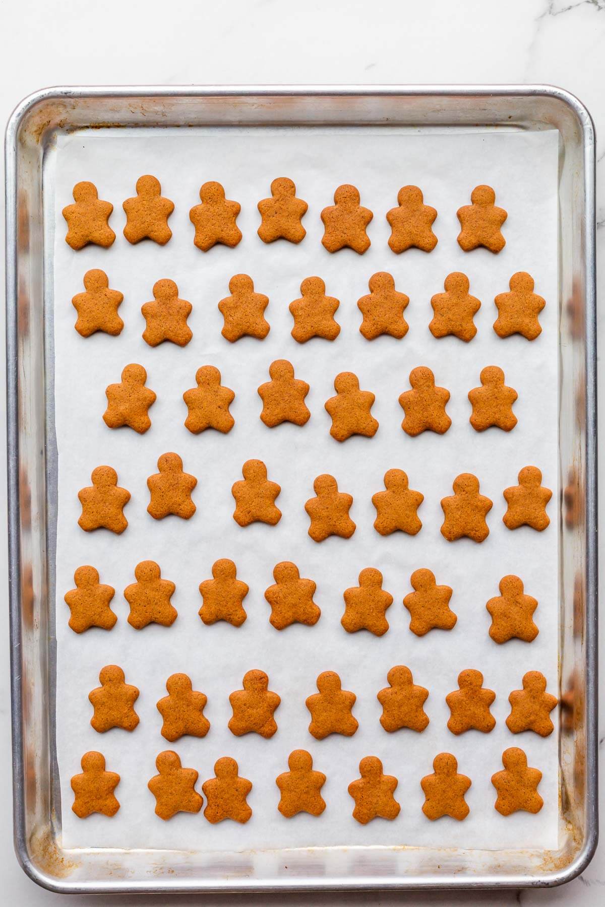 A baking sheet of baked tiny gingerbread men.