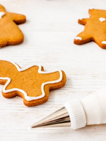 Using a piping bag fitted with a fine, small round tip to outline and decorate cutout gingerbread cookies with royal icing.