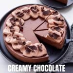 Slicing and serving a creamy dark chocolate cheesecake decorated with cocoa whipped cream and shards of dark chocolate.