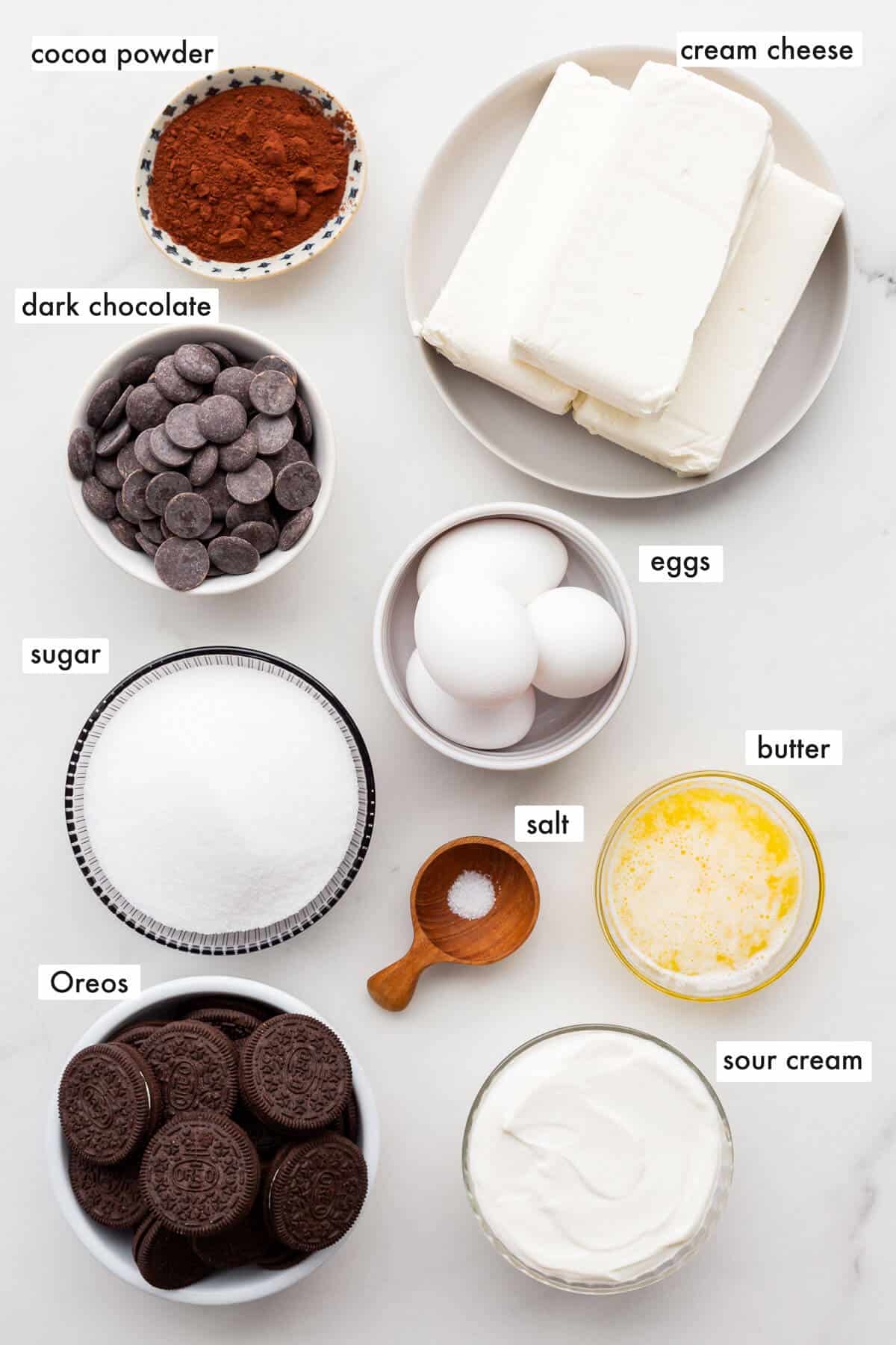 Ingredients to make a chocolate cheesecake with an Oreo crust, sour cream, and dark chocolate.