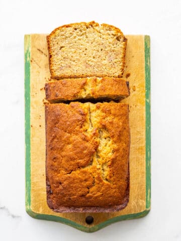 Banana bread on a cutting board being sliced.