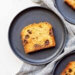 A slice of homemade moist zucchini bread with chocolate chips served on a black dessert plate.