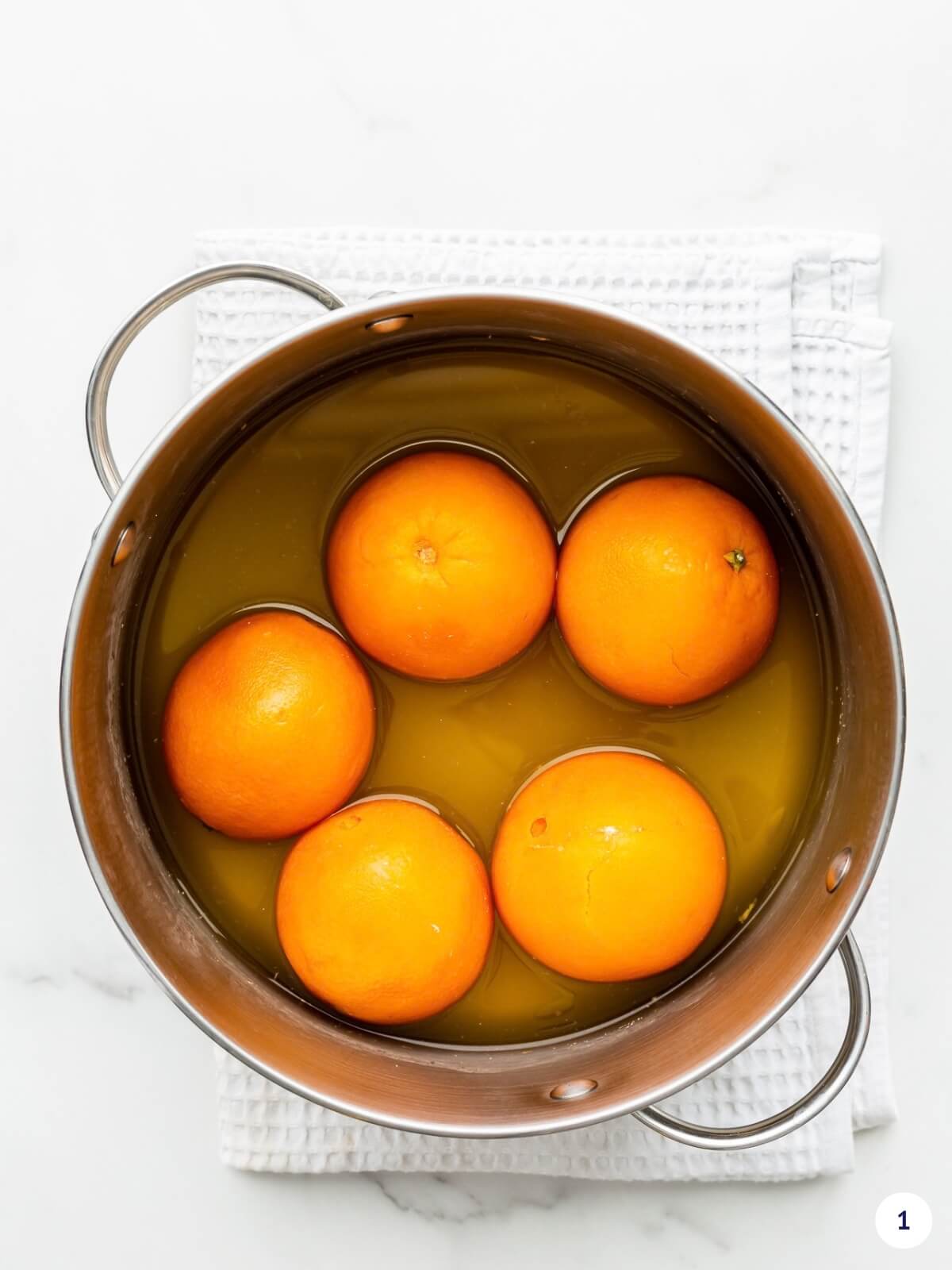 Boiling whole oranges in water until very soft to make orange marmalade from whole oranges.