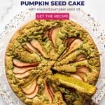 A pumpkin seed cake being sliced and served. The pumpkin seed cake is a vibrant green and has slices of pear on top.