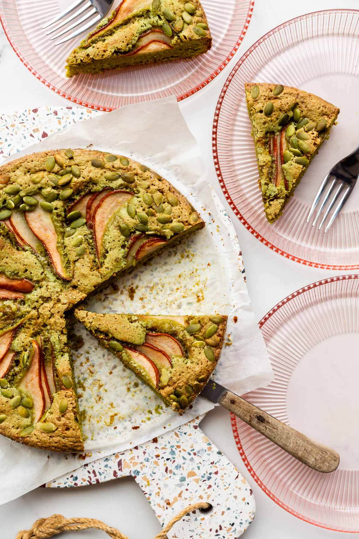 Slicing and serving a moist pumpkin seed cake on pink glass dessert plates.