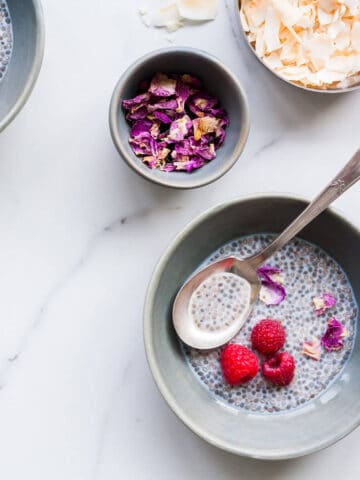 Chia pudding served with fresh raspberries, toasted coconut, and rose petals.