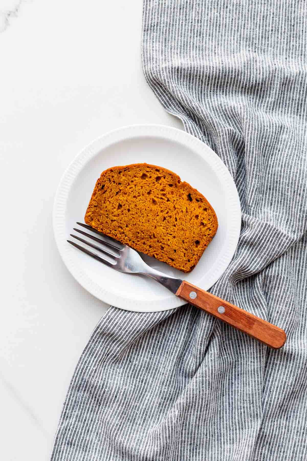 A slice of vegan pumpkin bread on a dessert plate, ready to be eaten.